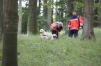 Daniela Bahn aus Paderborn schickt ihren Hund Baker auf die Suche nach Vermissten im Wald, ein weiterer Johanniter-Helfer steht mit einem Sanitätsrucksack zur ersten Hilfe bereit.