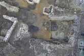 Das Luftbild eines Teils der Grabungsfläche zeigt neben den Mauern von Kellern und Parzellengrenzen auch die dunklen Verfärbungen der hochmittelalterlichen Gruben und Pfostenlöcher. © Eggenstein/Exca, R. Gündchen