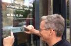 Freudestrahlend bringt der Haustechniker Thomas Senke das Schild an der Eingangstür 
des Weserrenaissance-Museums Schloss Brake an.
Foto: Schloss Brake