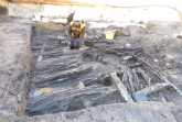 Archäologin Sarah Gonschorek legt die Hauswand des 13./14. Jahrhunderts zur weiteren Untersuchung und Dokumentation sorgfältig frei. Foto: LWL/Sven Spiong