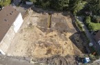 Das Drohnenfoto verdeutlicht, dass sich auf etwa der Hälfte der heutigen Grundstücke noch im 19. Jahrhundert der Burggraben erstreckte. Er zeichnet sich als dunkle Verfärbung im hinteren Grabungsareal deutlich vom anstehenden hellen Sandboden ab. Foto: Archäologie am Hellweg eG/Hussein-Oglü