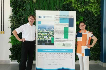 BiUH-Präsident Prof. Dr. Jürgen Kretschmann und Kanzlerin Prof. Dr. Guan Naijia vor einem Plakat mit dem Bauvorhaben für den Campus der neuen Hochschule. (Ziwei Du/BiUH)